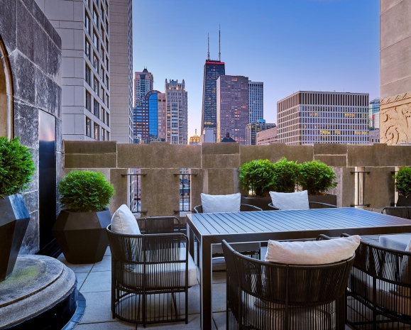 A balcony with a large outdoor table and views of downtown Chicago.